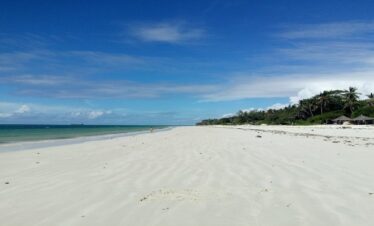 Beach shore at Cocoa Luxury Resort with white sand and clear blue ocean