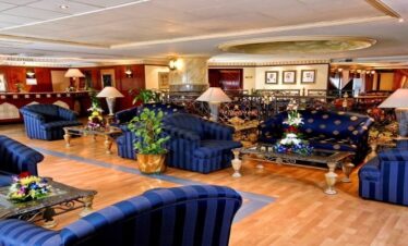 The ornate and classic lobby of Landmark Plaza Hotel in Dubai featuring striped blue velvet armchairs, gold-leaf accents, and a traditional reception desk