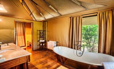 Luxurious en-suite tented bathroom at Sand River Mara Camp featuring a copper soaking tub and double vanity, part of our 3-Day Kenya Family Safari: Masai Mara & Big Five Adventure
