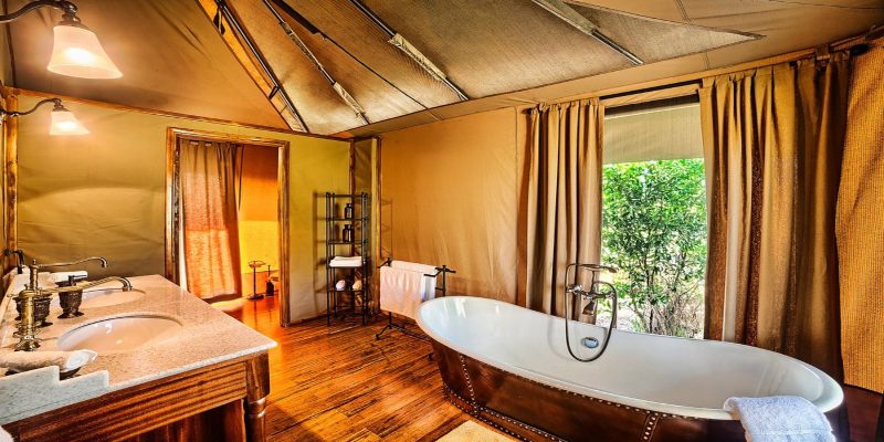 Luxurious en-suite tented bathroom at Sand River Mara Camp featuring a copper soaking tub and double vanity, part of our 3-Day Kenya Family Safari: Masai Mara & Big Five Adventure