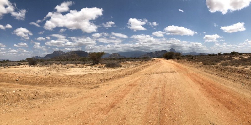 A wide dirt road leading toward distant volcanic mountains in Northern Kenya, a scenic route highlighted in our Chalbi Desert Guide: Kenya’s Stunning White Salt Plain