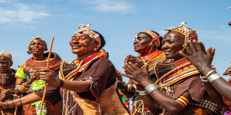 A Samburu warrior teaching a family about traditional beadwork and culture in a village Manyatta