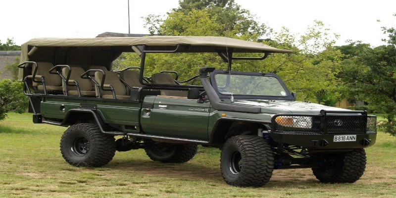 A green open-sided Toyota Land Cruiser 70 series safari vehicle with tiered seating, snorkel, and heavy-duty off-road tires for wildlife photography in Kenya.